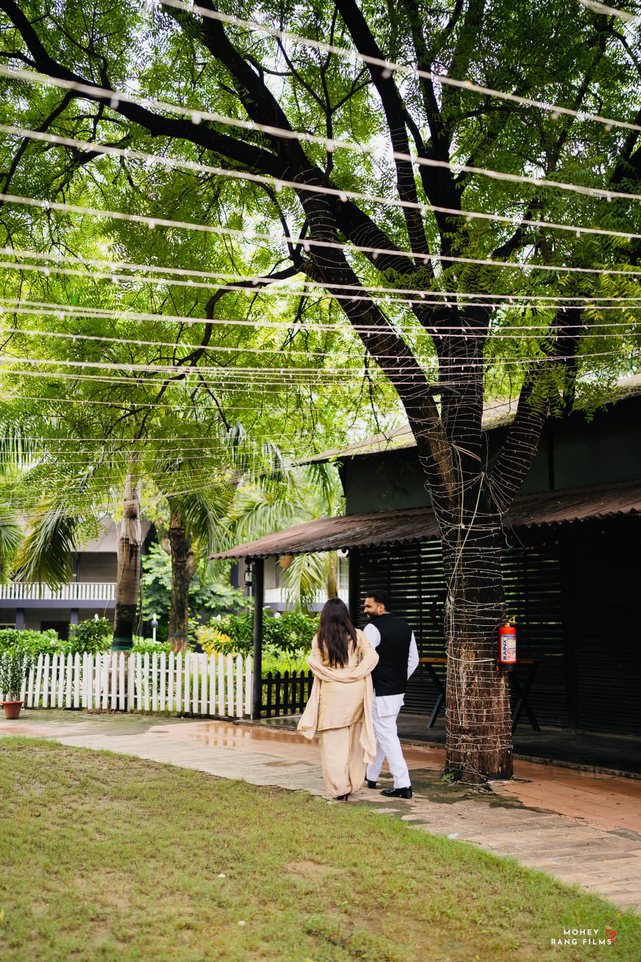 The couple strolling beneath fairy-lit trees